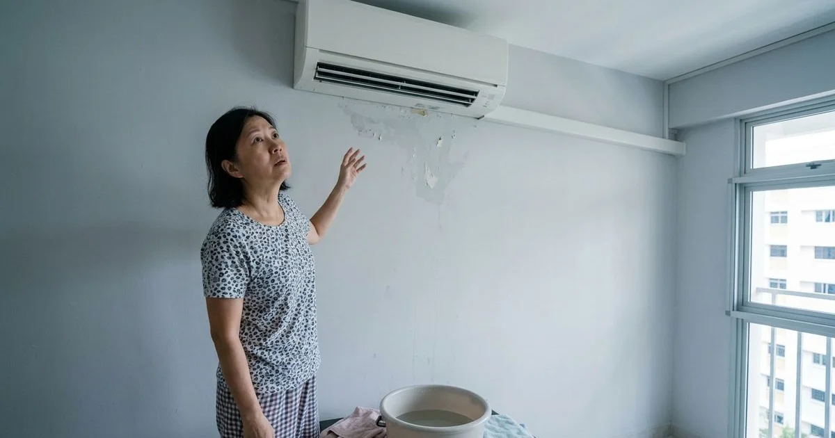 Singapore homeowner looking at wall-mounted aircon with concern
