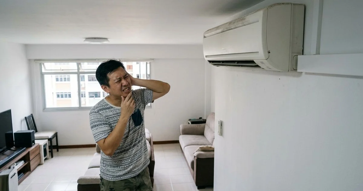 Singapore homeowner covering ear near noisy aircon indoor unit